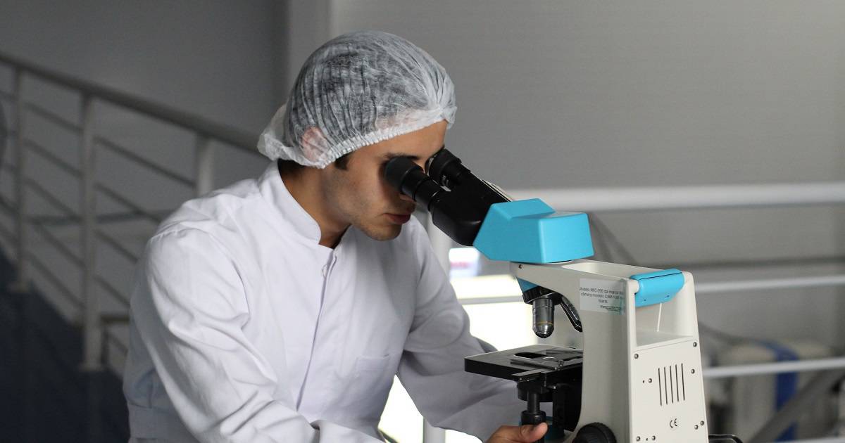 this a picture representing a doctor analysing a biopsy of suspected cancer under a microscope